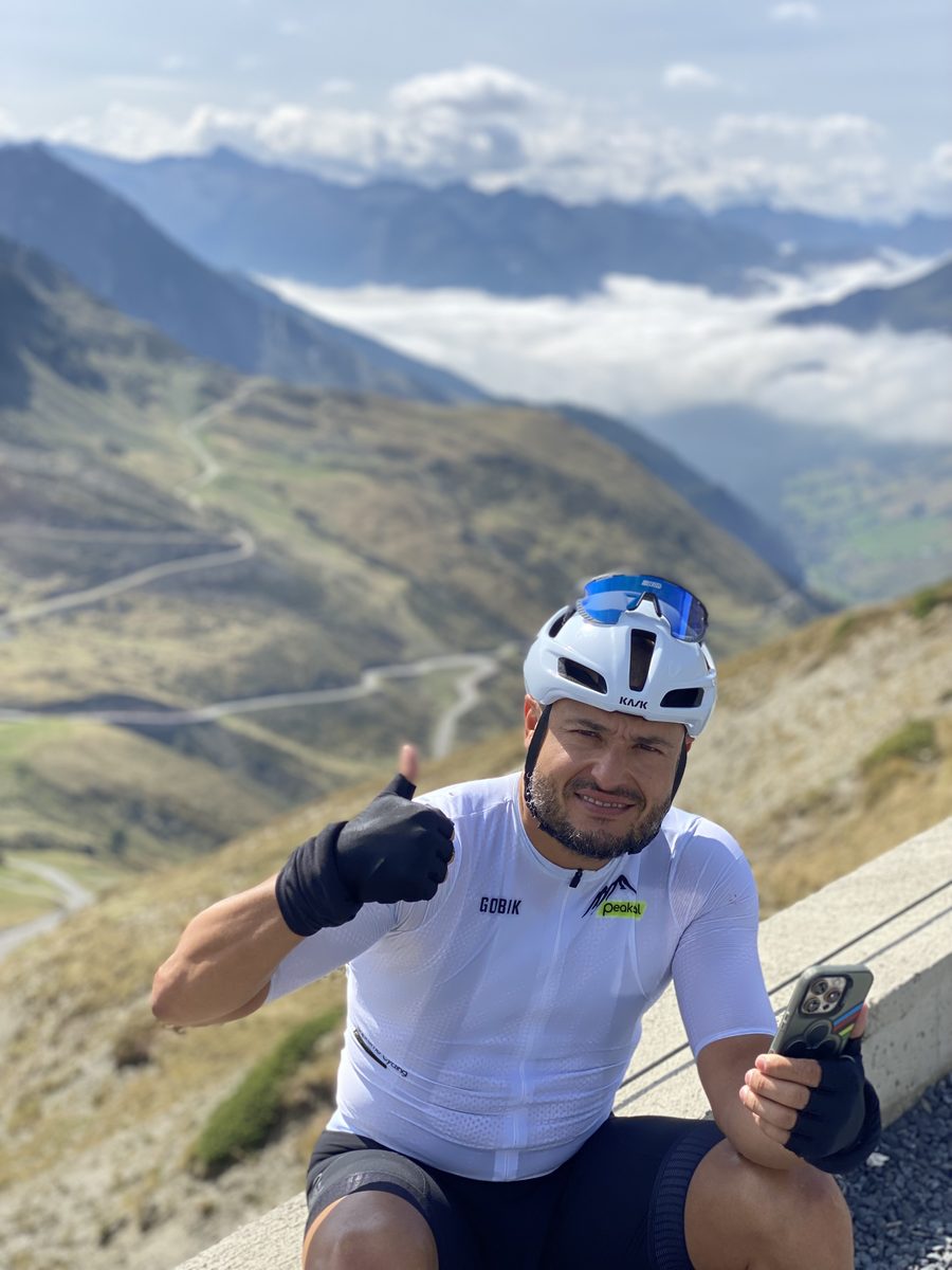 A PeaksPal rider above the cloud line with hairpins falling away below