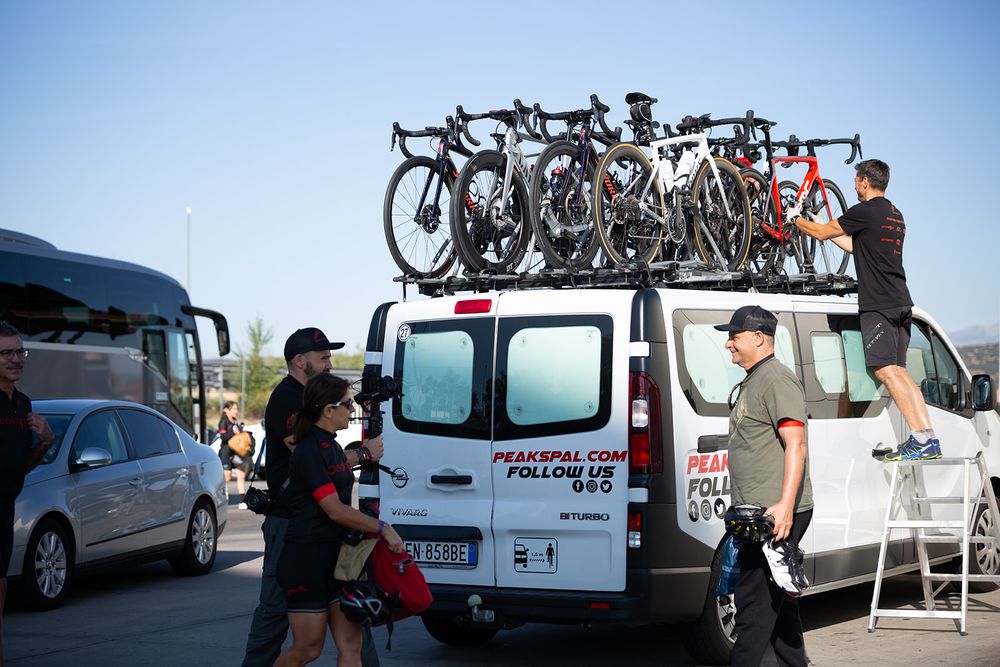 PeaksPal crew loading road bikes onto the roof rack of the support van