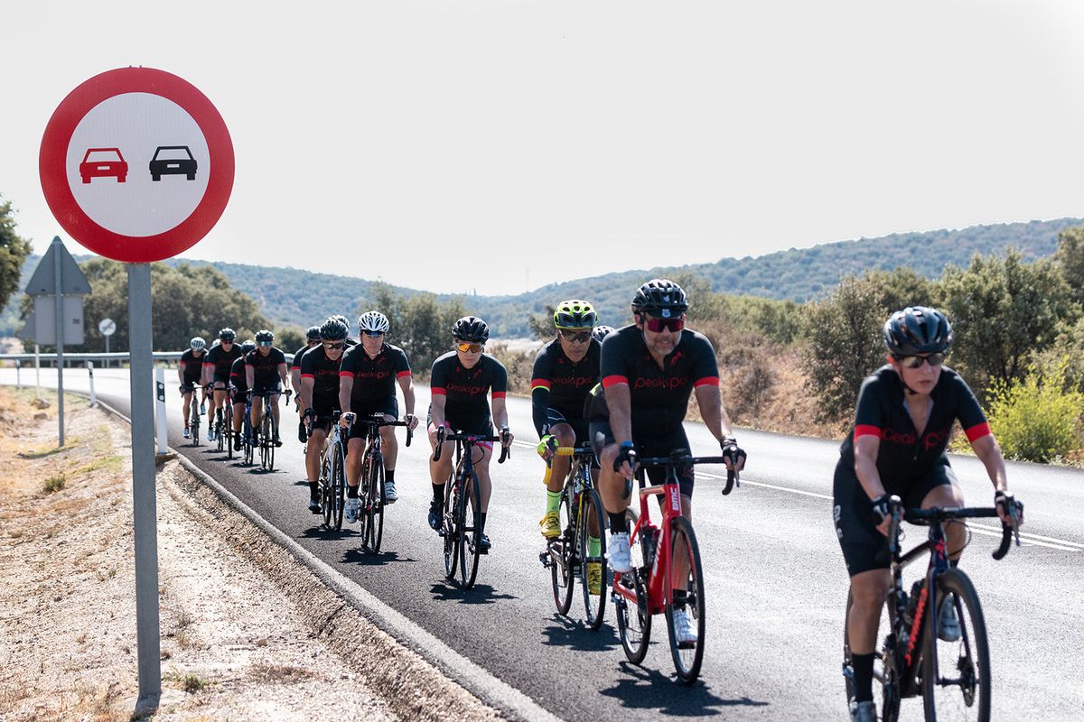 The group riding two abreast along an open road through dry hills